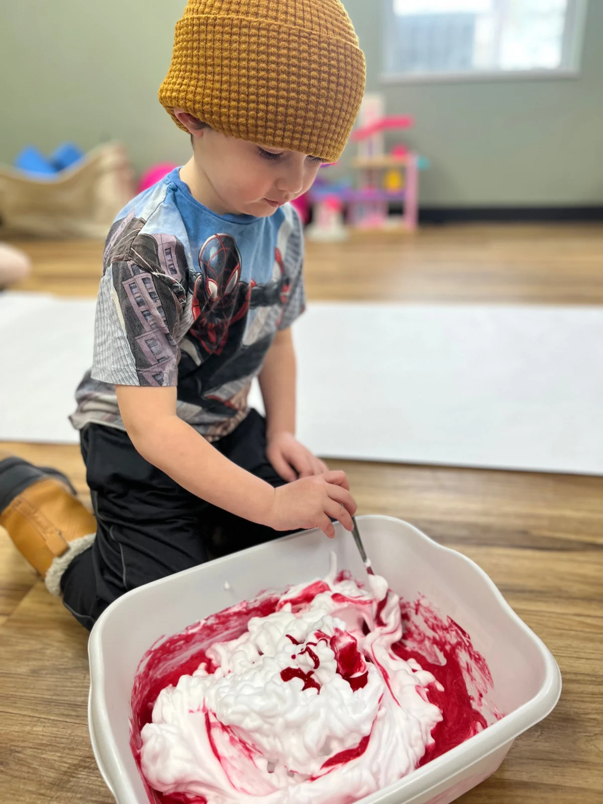 A young learner carefully stirring a colorful sensory experiment